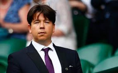Michael McIntyre in a black suit and purple tie caught at the camera.
